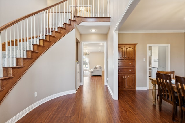 entrance foyer with ornamental molding, dark wood-type flooring, and a chandelier