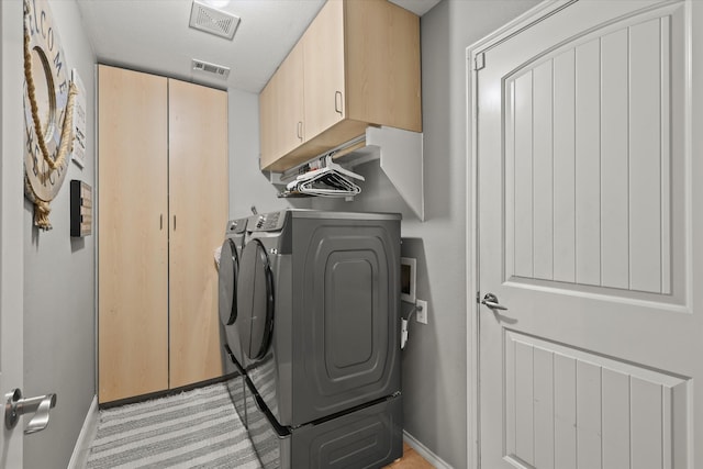 clothes washing area with washing machine and dryer and cabinets