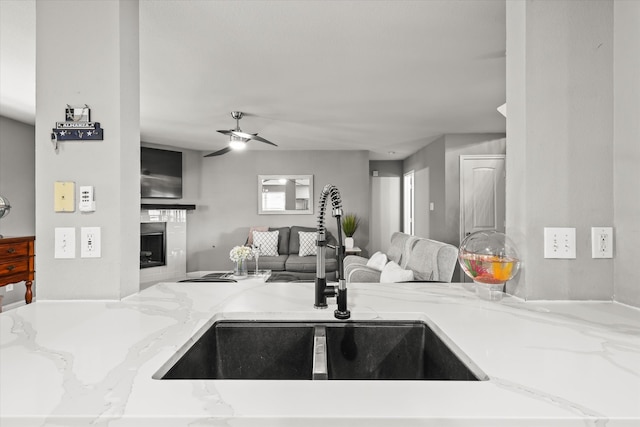 kitchen featuring light stone counters, sink, and ceiling fan