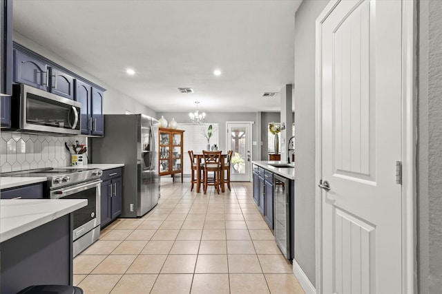 kitchen with blue cabinetry, sink, an inviting chandelier, and appliances with stainless steel finishes