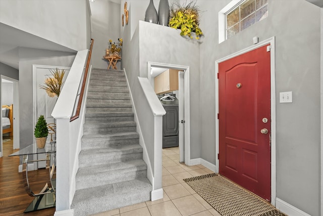 foyer entrance with light tile patterned floors, washer / dryer, and a high ceiling