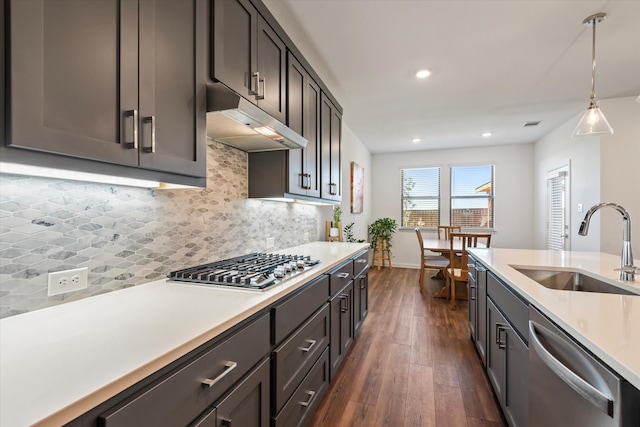 kitchen with tasteful backsplash, appliances with stainless steel finishes, dark wood-type flooring, pendant lighting, and sink