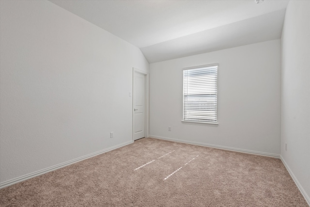 carpeted empty room with vaulted ceiling