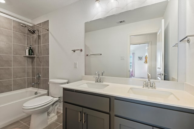 full bathroom featuring toilet, tiled shower / bath combo, vanity, and tile patterned flooring