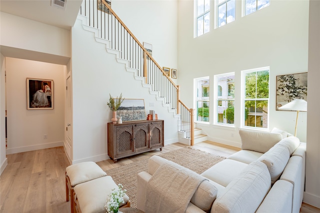 living room featuring a towering ceiling and light hardwood / wood-style flooring