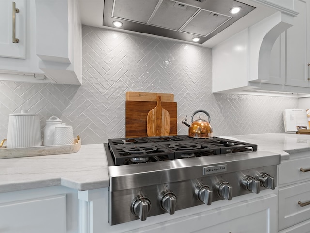 kitchen featuring stainless steel gas stovetop, white cabinetry, and light stone countertops