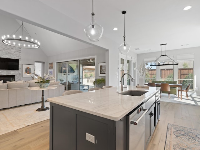 kitchen with a wealth of natural light, sink, a kitchen island with sink, and light wood-type flooring