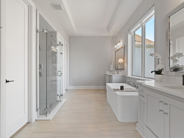 bathroom featuring vanity, a tray ceiling, shower with separate bathtub, and hardwood / wood-style floors