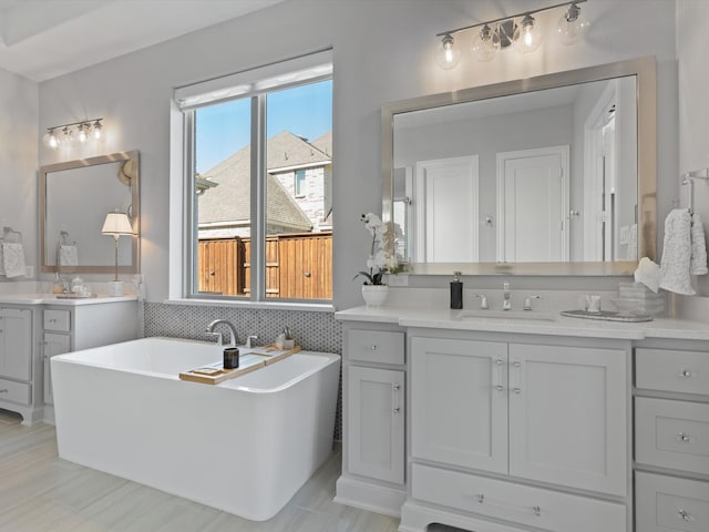 bathroom featuring vanity, decorative backsplash, and a washtub