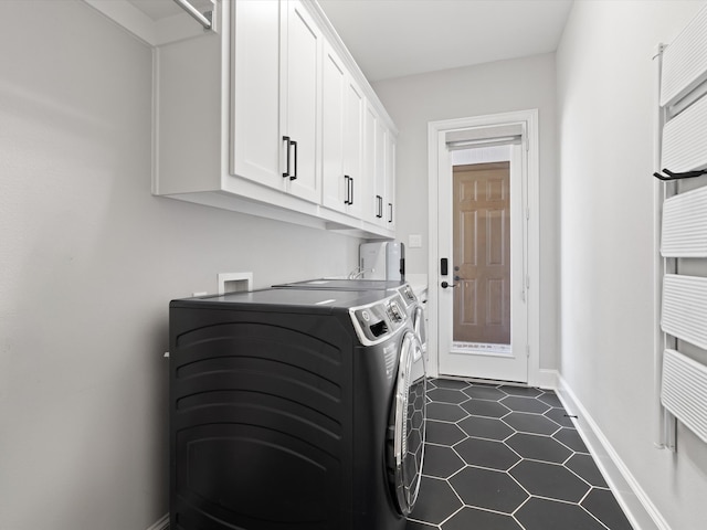 clothes washing area with dark tile patterned flooring, independent washer and dryer, and cabinets