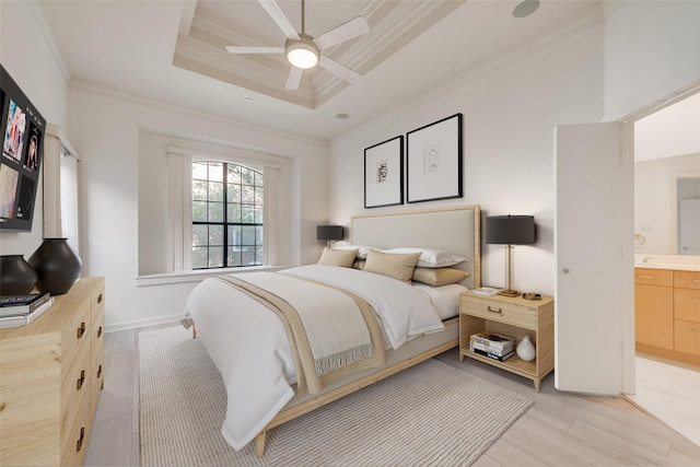 bedroom with ensuite bath, ornamental molding, a tray ceiling, ceiling fan, and light hardwood / wood-style floors