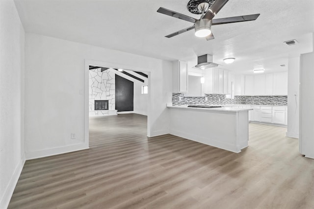 kitchen with kitchen peninsula, white cabinets, ceiling fan, backsplash, and wood-type flooring