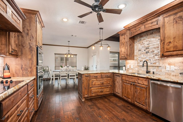 kitchen featuring sink, kitchen peninsula, pendant lighting, a textured ceiling, and appliances with stainless steel finishes