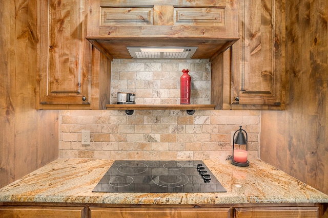 kitchen with black electric stovetop, light stone countertops, and tasteful backsplash