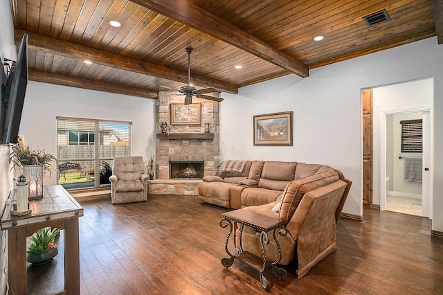 living room with wood ceiling, ceiling fan, dark wood-type flooring, beamed ceiling, and a stone fireplace