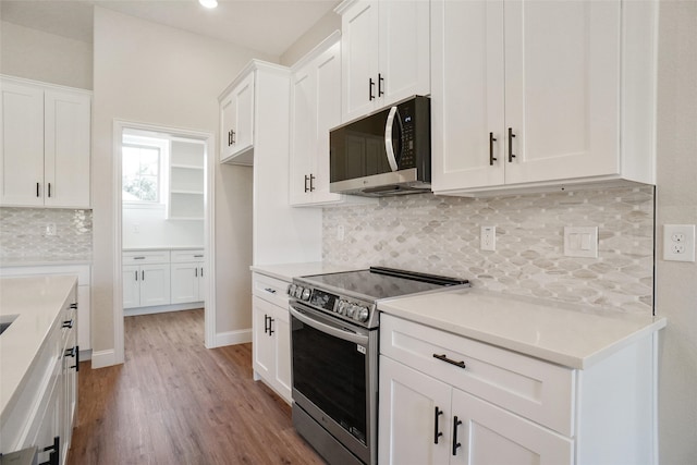 kitchen with white cabinetry, appliances with stainless steel finishes, light hardwood / wood-style floors, and backsplash