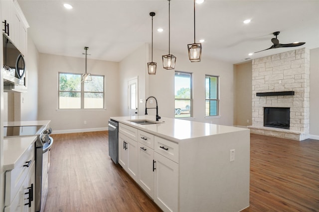 kitchen with a healthy amount of sunlight, white cabinets, sink, a kitchen island with sink, and appliances with stainless steel finishes