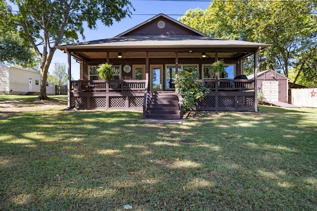 view of front facade with ceiling fan, covered porch, a front lawn, and a shed