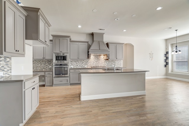 kitchen featuring custom range hood, light hardwood / wood-style floors, stainless steel appliances, and gray cabinets