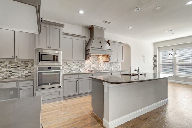 kitchen with stainless steel appliances, tasteful backsplash, sink, and light wood-type flooring