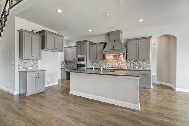 kitchen with gray cabinets, dark wood-type flooring, appliances with stainless steel finishes, and premium range hood