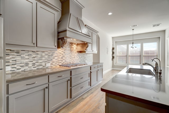 kitchen with gray cabinetry, light hardwood / wood-style floors, sink, and stainless steel gas stovetop