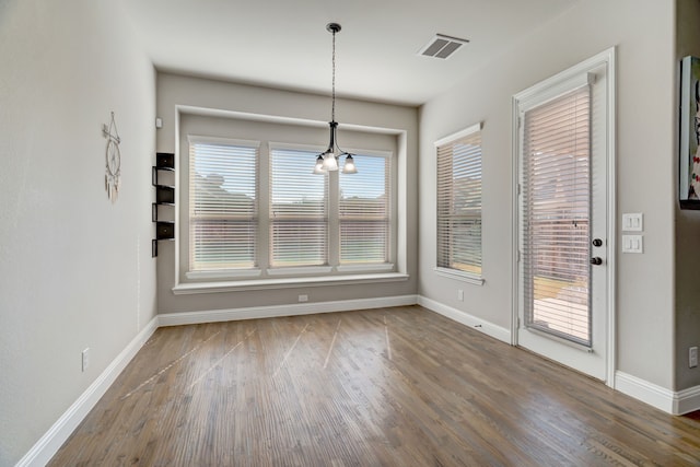 unfurnished dining area featuring a chandelier and dark hardwood / wood-style flooring