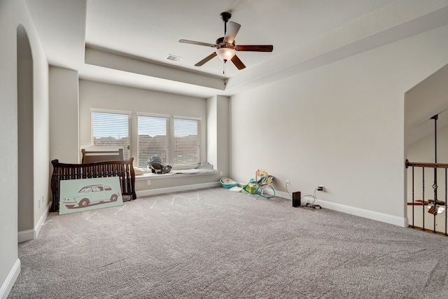 interior space featuring carpet floors, a tray ceiling, and ceiling fan