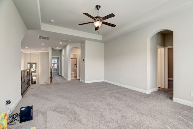 unfurnished living room with a raised ceiling, carpet floors, and ceiling fan