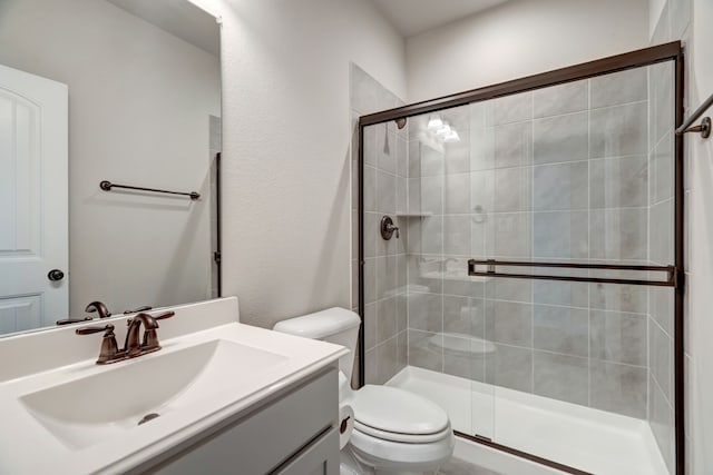 bathroom with vanity, a shower with shower door, and toilet