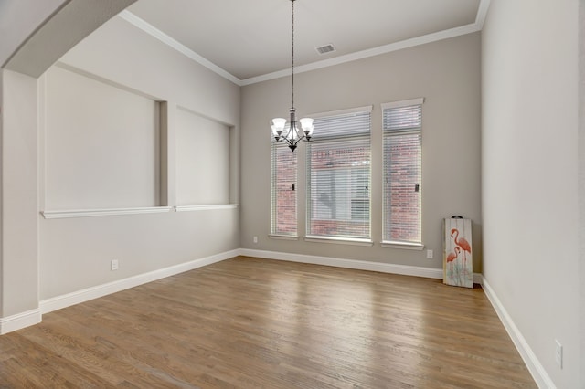 empty room featuring ornamental molding, hardwood / wood-style floors, and a chandelier