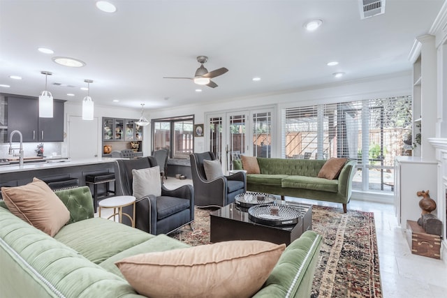 living room featuring sink, ornamental molding, and ceiling fan