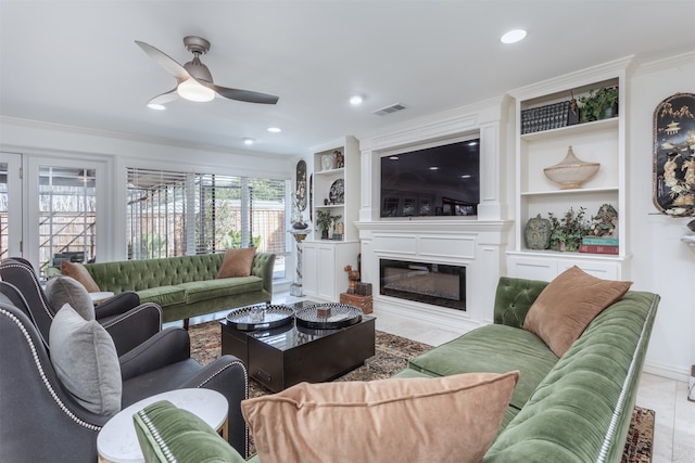 living room featuring built in shelves, a large fireplace, ornamental molding, and ceiling fan