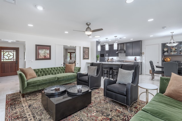 living room featuring sink, ornamental molding, and ceiling fan