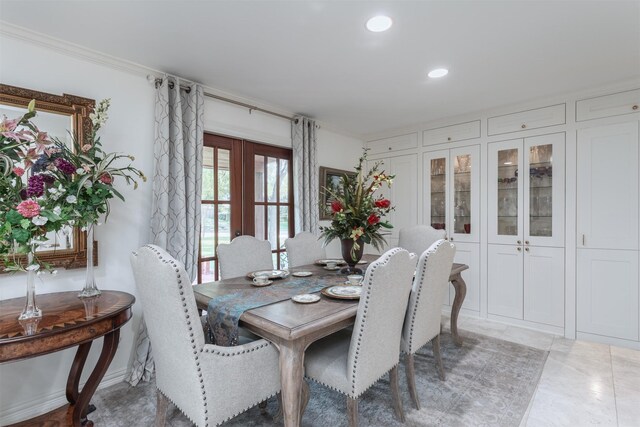 tiled dining room with ornamental molding and french doors