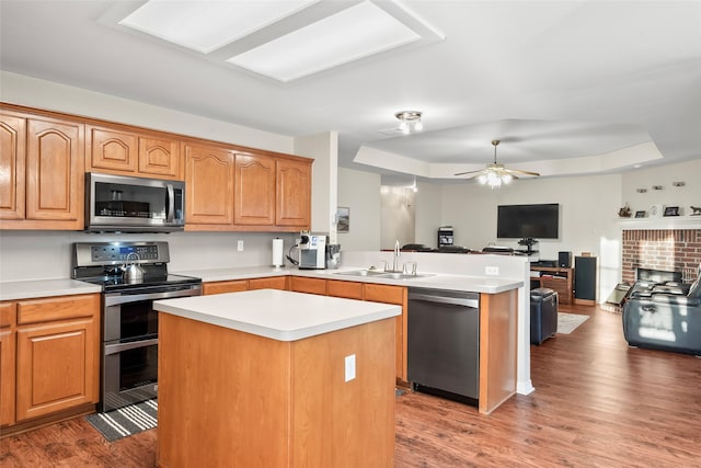 kitchen featuring appliances with stainless steel finishes, a center island, dark hardwood / wood-style floors, and sink