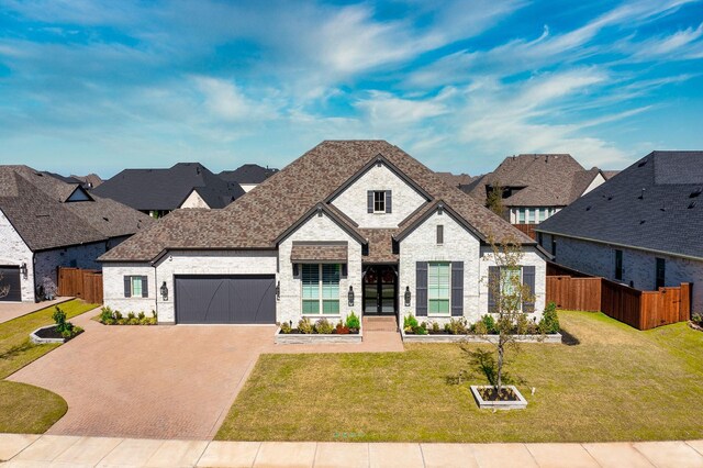 french country inspired facade featuring a front yard and a garage