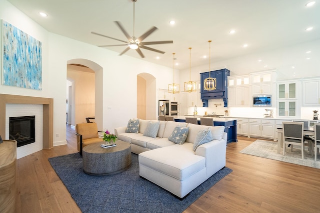 living room with sink, light wood-type flooring, and ceiling fan