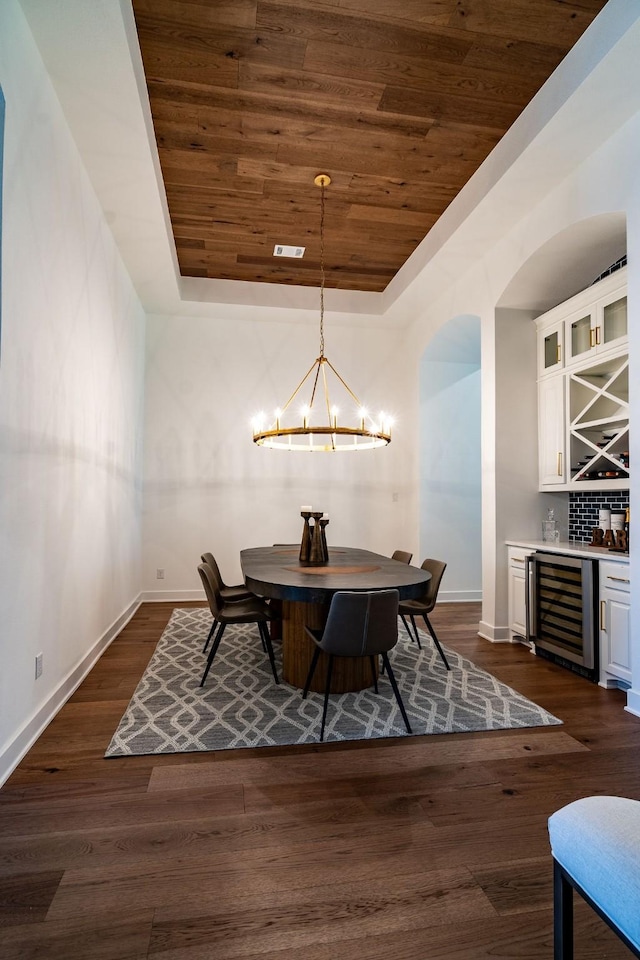 dining area featuring a notable chandelier, bar, wooden ceiling, a raised ceiling, and wine cooler