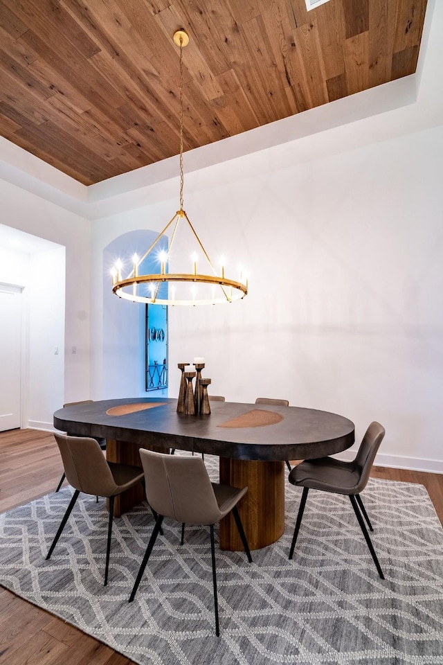 dining area with wooden ceiling, a raised ceiling, an inviting chandelier, and dark hardwood / wood-style flooring