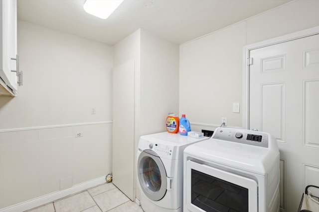 washroom with cabinets, washing machine and clothes dryer, and light tile patterned floors