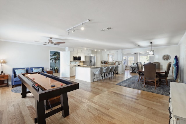 playroom with ceiling fan, crown molding, and light wood-type flooring