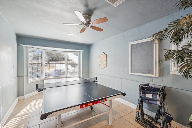 rec room with a textured ceiling, ceiling fan, and light tile patterned floors