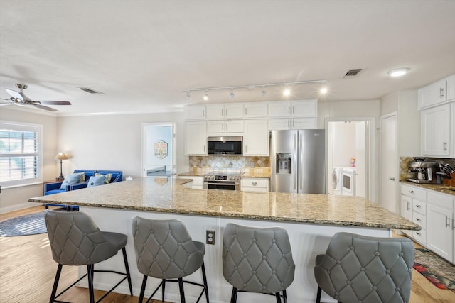 kitchen with appliances with stainless steel finishes, light hardwood / wood-style flooring, and white cabinetry