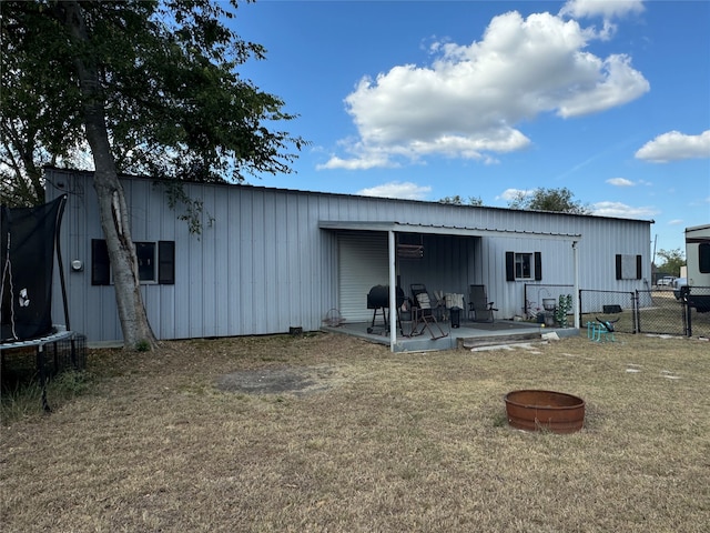 back of house featuring a patio, a trampoline, and a lawn