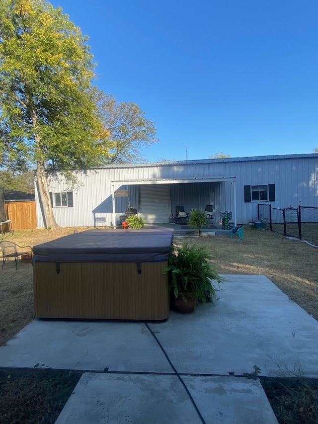 back of property featuring a hot tub, a patio, and a yard