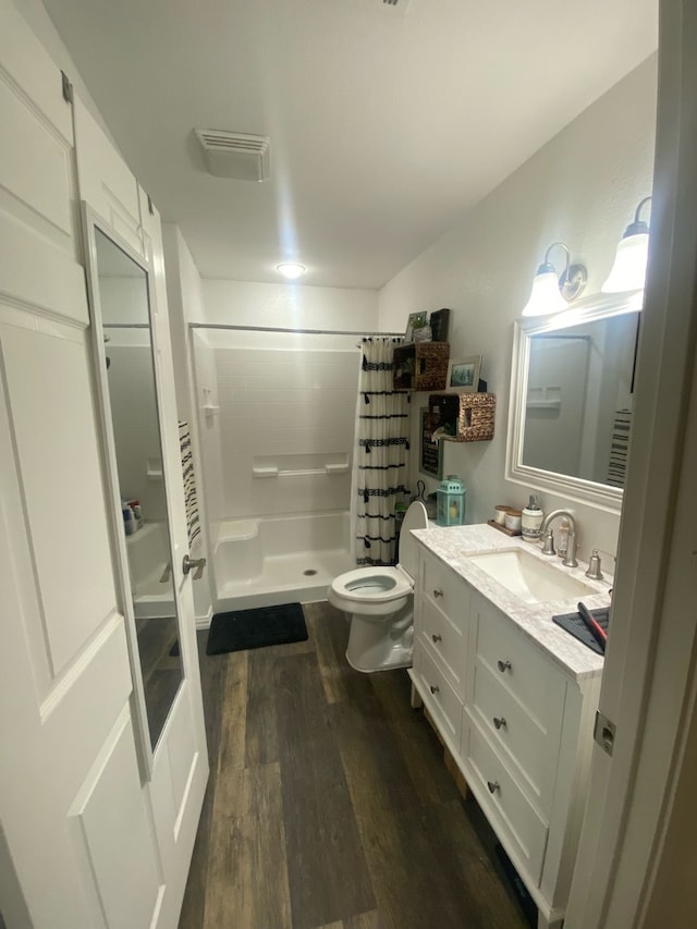 bathroom with a shower with curtain, wood-type flooring, vanity, and toilet