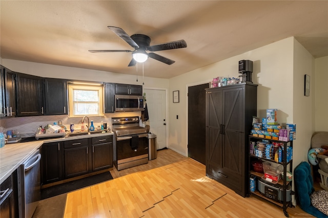 kitchen with sink, light wood-type flooring, ceiling fan, stainless steel appliances, and decorative backsplash