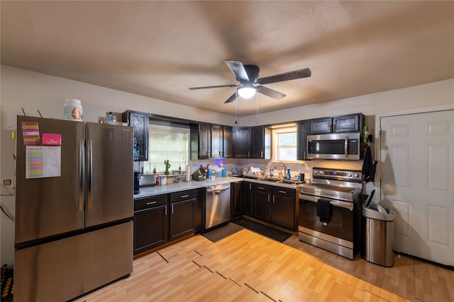 kitchen with sink, light hardwood / wood-style floors, stainless steel appliances, ceiling fan, and decorative backsplash