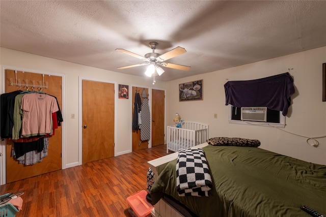 bedroom with cooling unit, a textured ceiling, hardwood / wood-style flooring, and ceiling fan